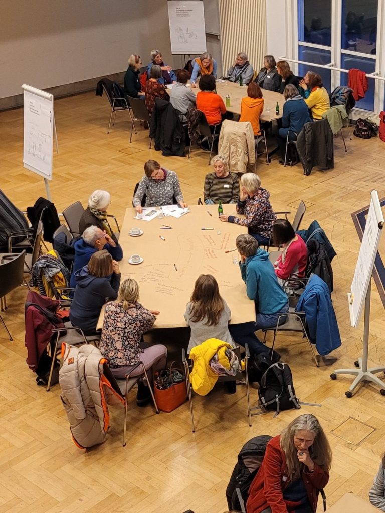 Gruppen von Frauen sitzen an Tischen in einem World Café.