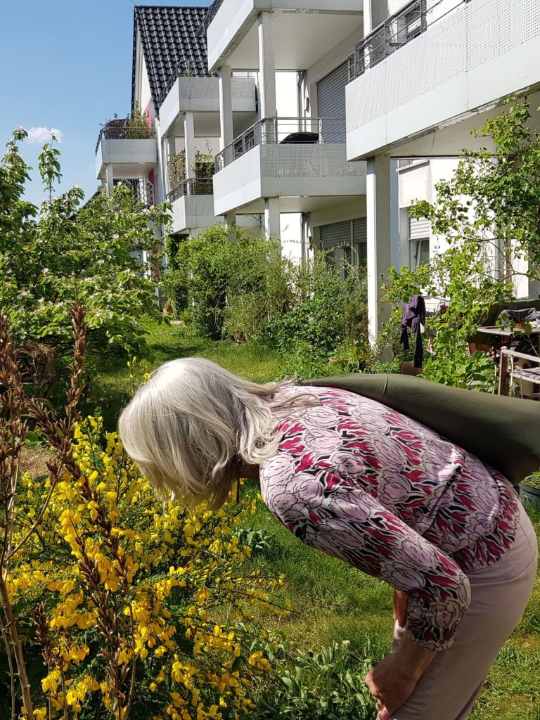 Eine Frau beugt sich über eine blühende Pflanze.