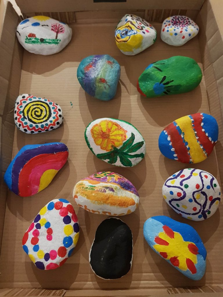 Bunt bemalte Steine liegen in einem Karton.